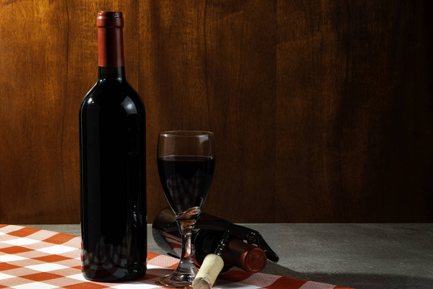 Bottle of red wine in wine cellar for tasting. Red wood background. Wine tradition and culture concept. - Photo, Image