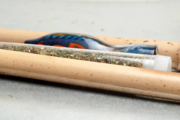 Vue rapprochée de la marijuana séchée dans un tube en plastique et une pipe à fumer. Concept de toxicomanie. Concept de marijuana médicale
  - Photo, image