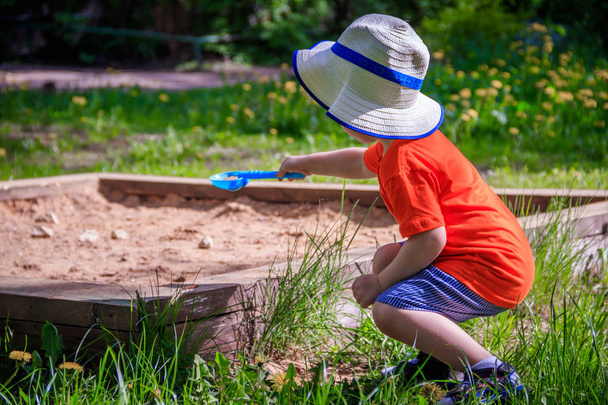 Little boy with a bucket and a shovel playing in the sand. Summer nature - Photo, Image