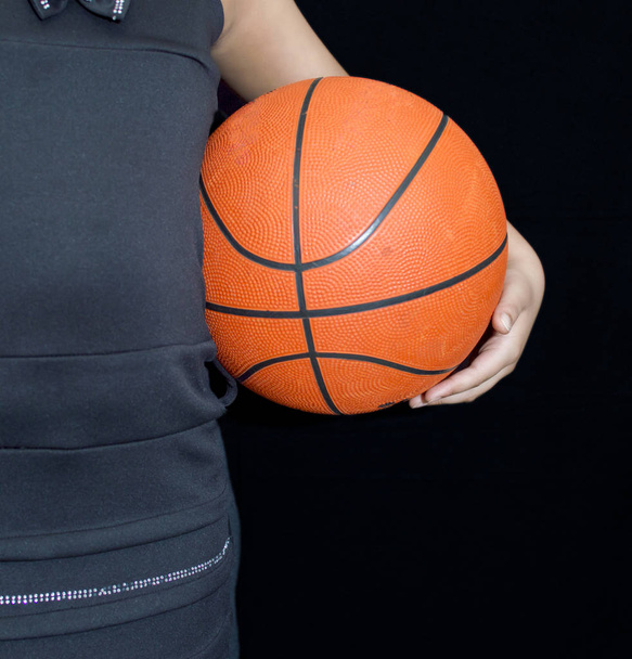 A girl holding basketball in hands on the sides - Фото, изображение