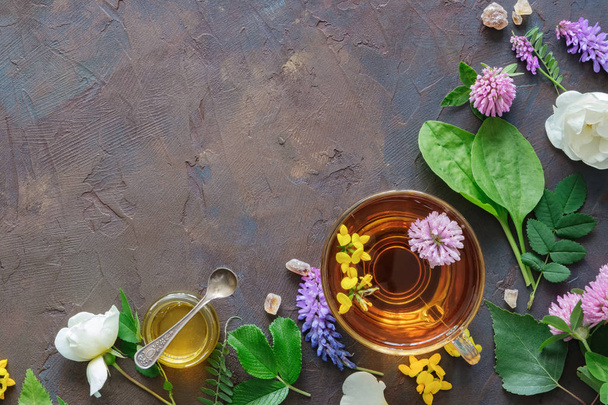 Стеклянная кружка здорового травяного чая, лекарственные травы и небольшая банка меда
. - Фото, изображение