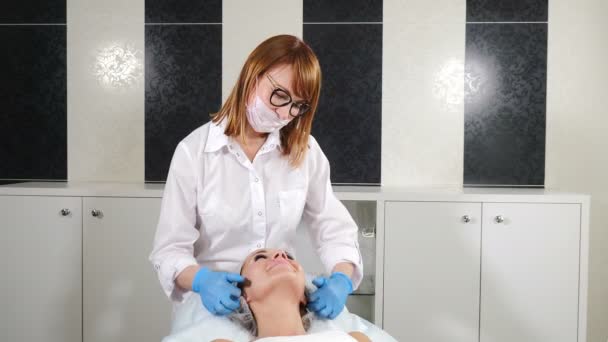 Videoportrait of happy friendly beautician smiling at camera. Middle-aged cosmetologist in white lab coat smiling while beauty procedure. 4 k - Footage, Video