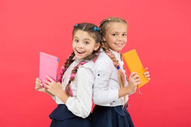 These books are absolutely genius. Genius little children smiling on red background. Happy genius girls or wonder kids with books. Small schoolgirls holding books with genius ideas - Фото, изображение