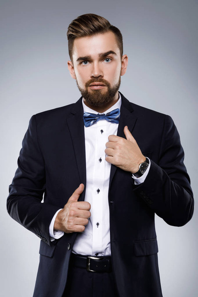 Stylish handsome man wearing a classic suit with bow-tie - Fotó, kép