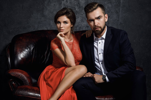 Attractive young couple is sitting on the leather sofa - Fotó, kép