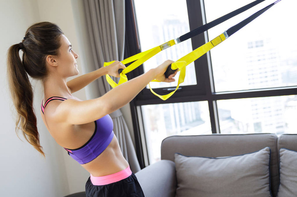 Woman during her  workout at home with suspension straps - Φωτογραφία, εικόνα