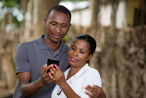 улыбающаяся пара с мобильным телефоном снаружи
 - Фото, изображение