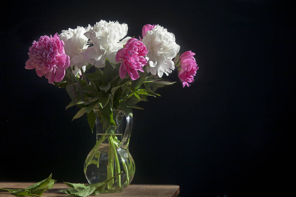 csokor fehér és vörös pünkösdi rózsa átlátszó vázában sötét háttér - Fotó, kép