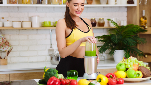 Woman Making Vegan Juice With Machine In Kitchen - Foto, imagen