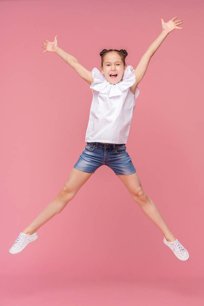 Funny little girl laughing, jumping on pink background - Photo, Image