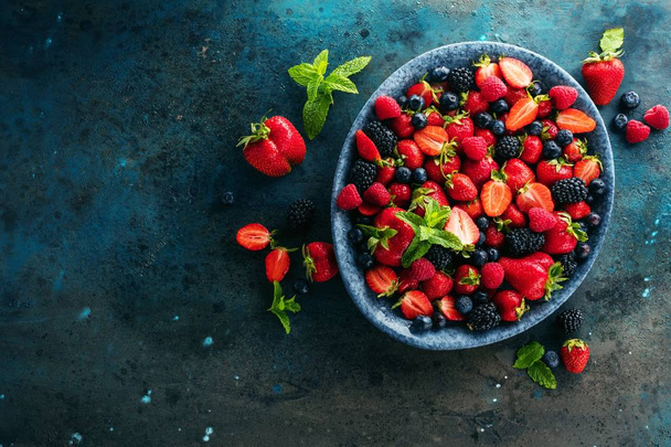 top view of fresh ripe berries in bowl on grey surface - Zdjęcie, obraz