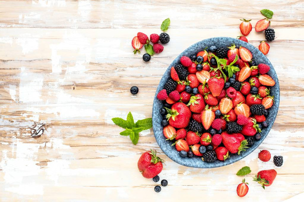 Draufsicht auf frische reife Erdbeeren, Blaubeeren und Brombeeren auf Holztisch mit Kopierraum - Foto, Bild