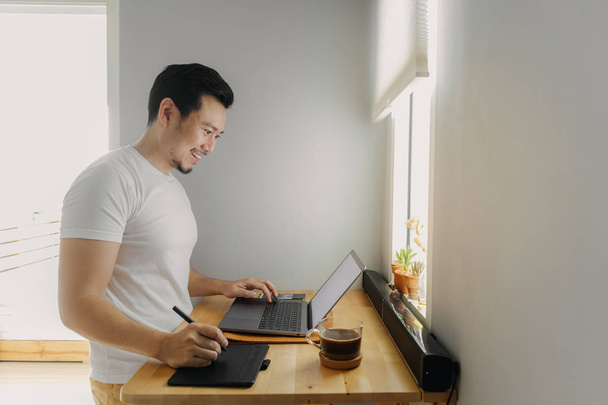 Happy freelancer man is working on his laptop. Concept of freelance creative works. - 写真・画像