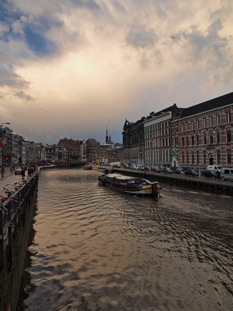 Amsterdamski kanał Amstel z typowymi holenderskimi domami i łodzi  - Zdjęcie, obraz