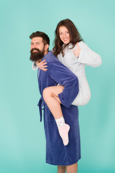 Trust and support. True love. Lets stay at home. They are closest people. Support in any time. Reliable support. Handsome young man piggybacking beautiful woman. Couple in bathrobes having fun - Φωτογραφία, εικόνα