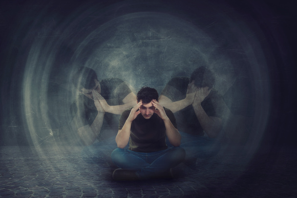 hombre sentado en el suelo, las manos a la cabeza, sufren emociones divididas en
 - Foto, Imagen