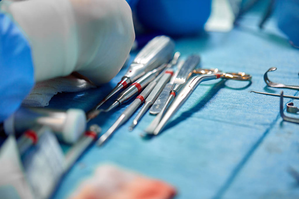 Χειρουργικά όργανα και όργανα, όπως νυστέρια, λαβίδες και λαβίδες, βρίσκονται στο τραπέζι για χειρουργική επέμβαση. Ιατρική, χειρουργική, διάσωση ζωών. - Φωτογραφία, εικόνα