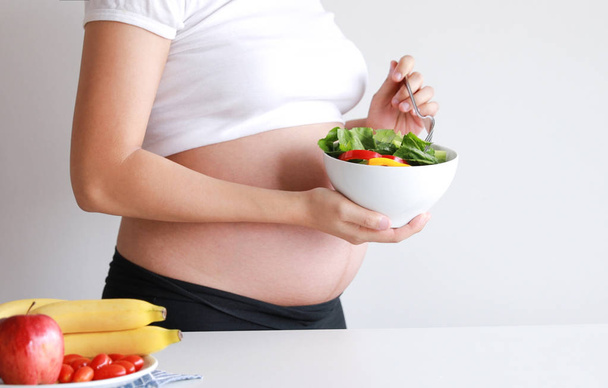妊娠中の女性は野菜サラダ、フルーツ、ジュース、ミルク、健康食品を食べる - 写真・画像