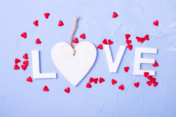Word love from white wooden letters and little red hearts on blu - Zdjęcie, obraz