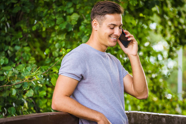 Young man talking on smartphone outdoor - Fotoğraf, Görsel