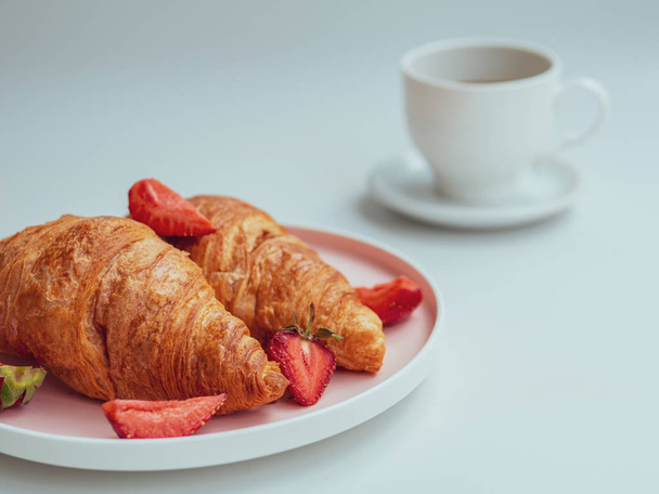 Summer morning with croissants, fresh breakfast with strawberry, and coffee. Closeup - Photo, Image