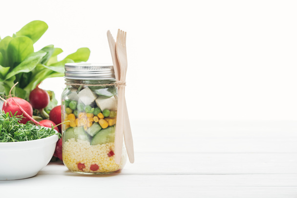 ensalada de verduras frescas en frasco de vidrio cerca de rábano aislado en blanco
 - Foto, Imagen
