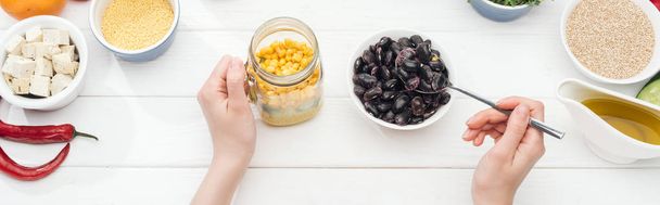 cropped view of woman adding beans in jar with salad on wooden white table, panoramic shot - Photo, Image