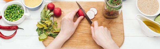 cropped view of woman cutting radish on wooden chopping board, panoramic shot - Photo, Image