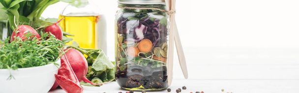 verse groente salade in glazen pot in de buurt van specerijen en radijs geïsoleerd op witte, panoramische foto - Foto, afbeelding