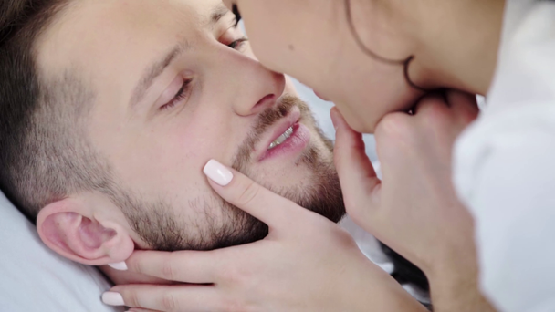 yakışıklı sakallı adam kadın bakarak seçici odak, yüze dokunmave yatak odasında öpüşme  - Video, Çekim
