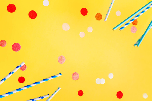 Colorful drinking straws for beverage and colored confetti on bright yellow background - Fotografie, Obrázek