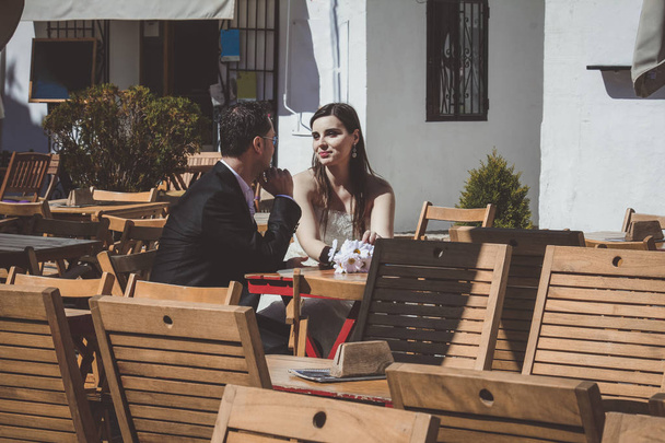 Young wedding couple on their wedding day, relaxing in a bar and having a beer - Photo, Image