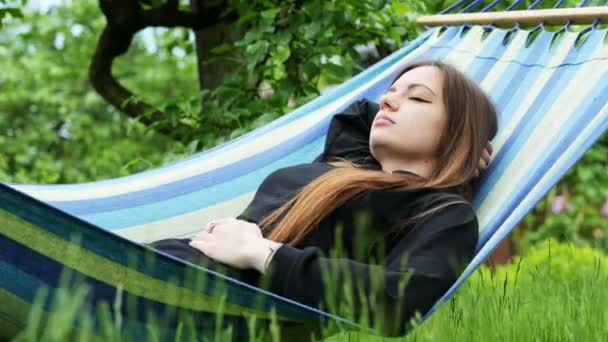 Hermosa joven que duerme en una hamaca en el jardín, descansando y dormitando
 - Imágenes, Vídeo