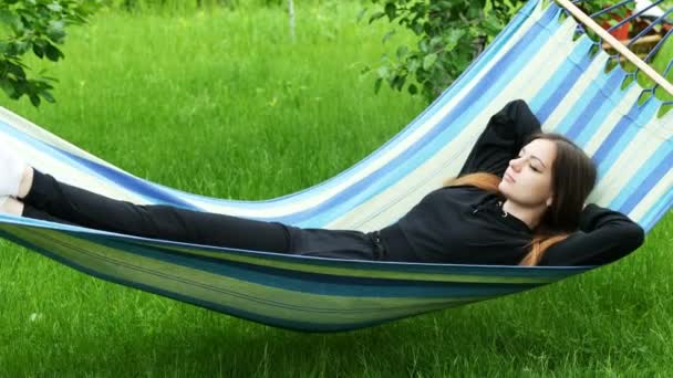 Красива молода жінка лежить в гамаку в саду, відпочиває і розкладається
 - Кадри, відео