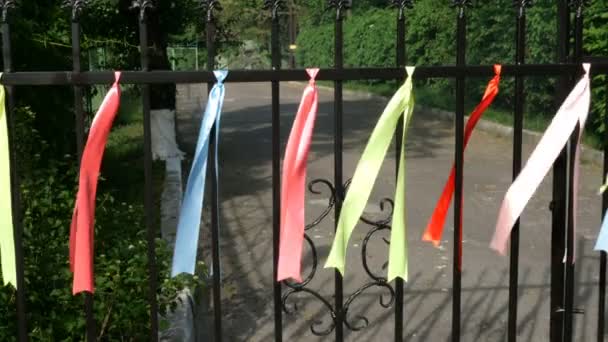 Разноцветные ленты трепещут на металлическом заборе в парке
. - Кадры, видео