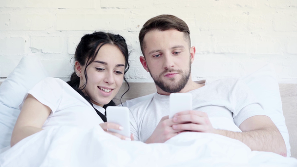foco seletivo do casal usando smartphones e falando na cama
  - Filmagem, Vídeo