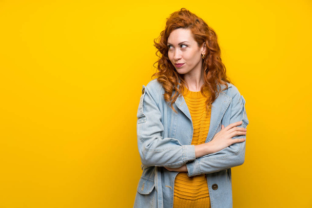 Redhead vrouw over geïsoleerde gele achtergrond staande en het denken van een idee - Foto, afbeelding