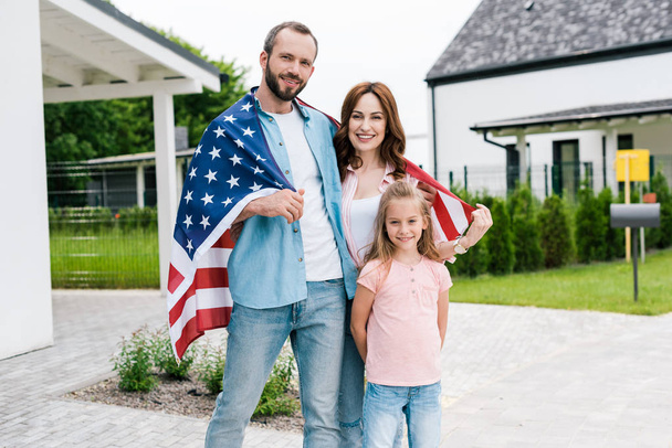 felice famiglia in piedi con bandiera americana vicino casa
  - Foto, immagini