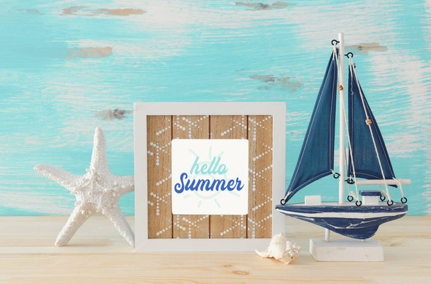 Nautical concept with photo frame and sail boat over wooden table - Fotó, kép