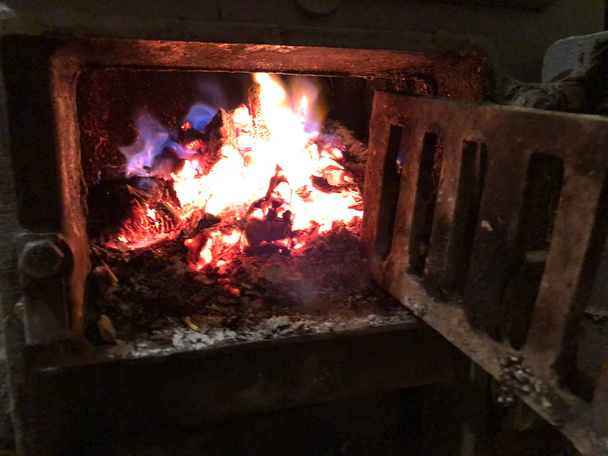 fuego ardiente en la estufa con una puerta de hierro
 - Foto, imagen