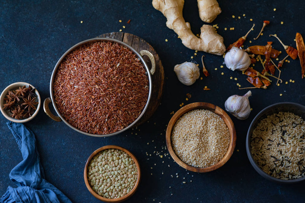 Various types of rice and grains with spices in bowls on blue background  - Foto, afbeelding