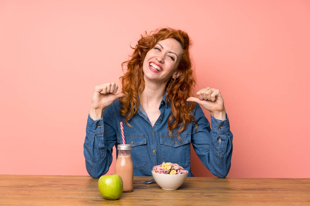 Redhead woman having breakfast cereals and fruit proud and self-satisfied - Фото, зображення