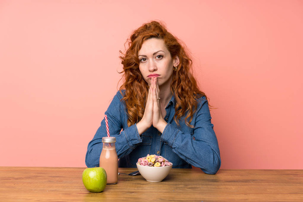 Redhead woman having breakfast cereals and fruit pleading - Photo, image