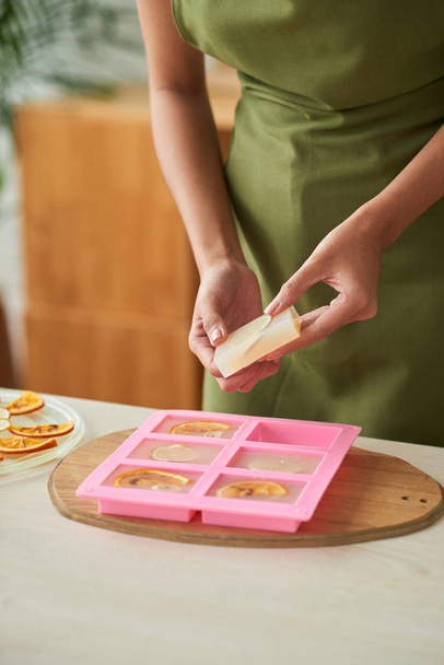 częściowy widok kobiety domowej roboty mydło z pomarańczowymi plasterkami  - Zdjęcie, obraz