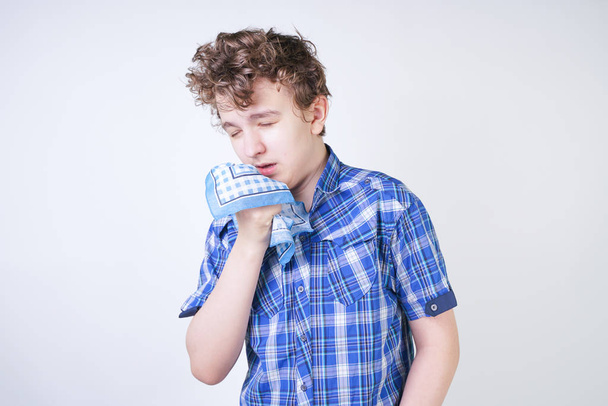 Allergy Boy Child with runny nose holding a handkerchief. Teenager is having bad health and standing on white studio background alone. - Photo, Image