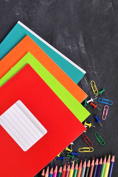 Bright stationery on a black Board background notebooks, pencils, scissors and others. - Zdjęcie, obraz