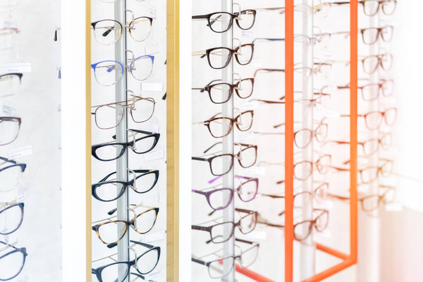 光学小売店で多くのメガネ列。メガネショップディスプレイ上の異なるアイウェアフレームの豊富な品揃えの選択 - 写真・画像