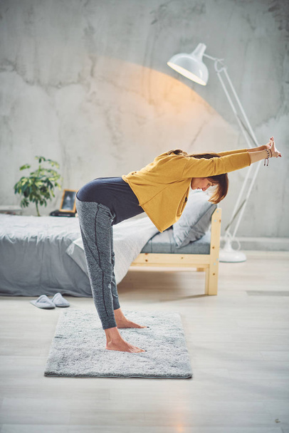 Full length of gorgeous fit brunette stretching on rug in the morning. Yoga practicing concept. - 写真・画像