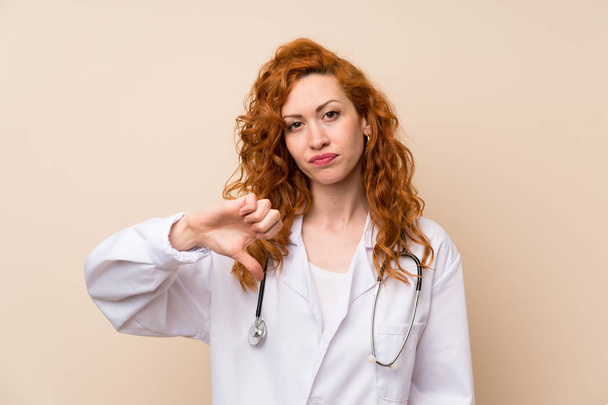 Redhead doctor woman showing thumb down sign - Fotó, kép
