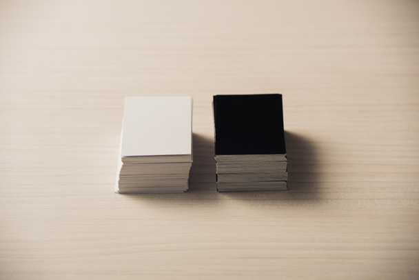 pilas de tarjetas de visita vacías blancas y negras en la superficie de madera blanca
 - Foto, Imagen